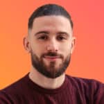 Portrait of Arezki Amiri, a young man with a well-groomed beard, wearing a burgundy sweater, on an orange gradient background.