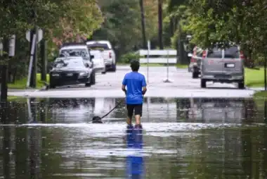 A Man Walks A Dog Through A Flooded Street In Charleston, S.c., On Tuesday.